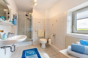 Une salle de bain avec une douche, des toilettes, un lavabo et une fenêtre.
