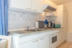 Une cuisine avec des meubles blancs, un évier, une cuisinière et un grille-pain.