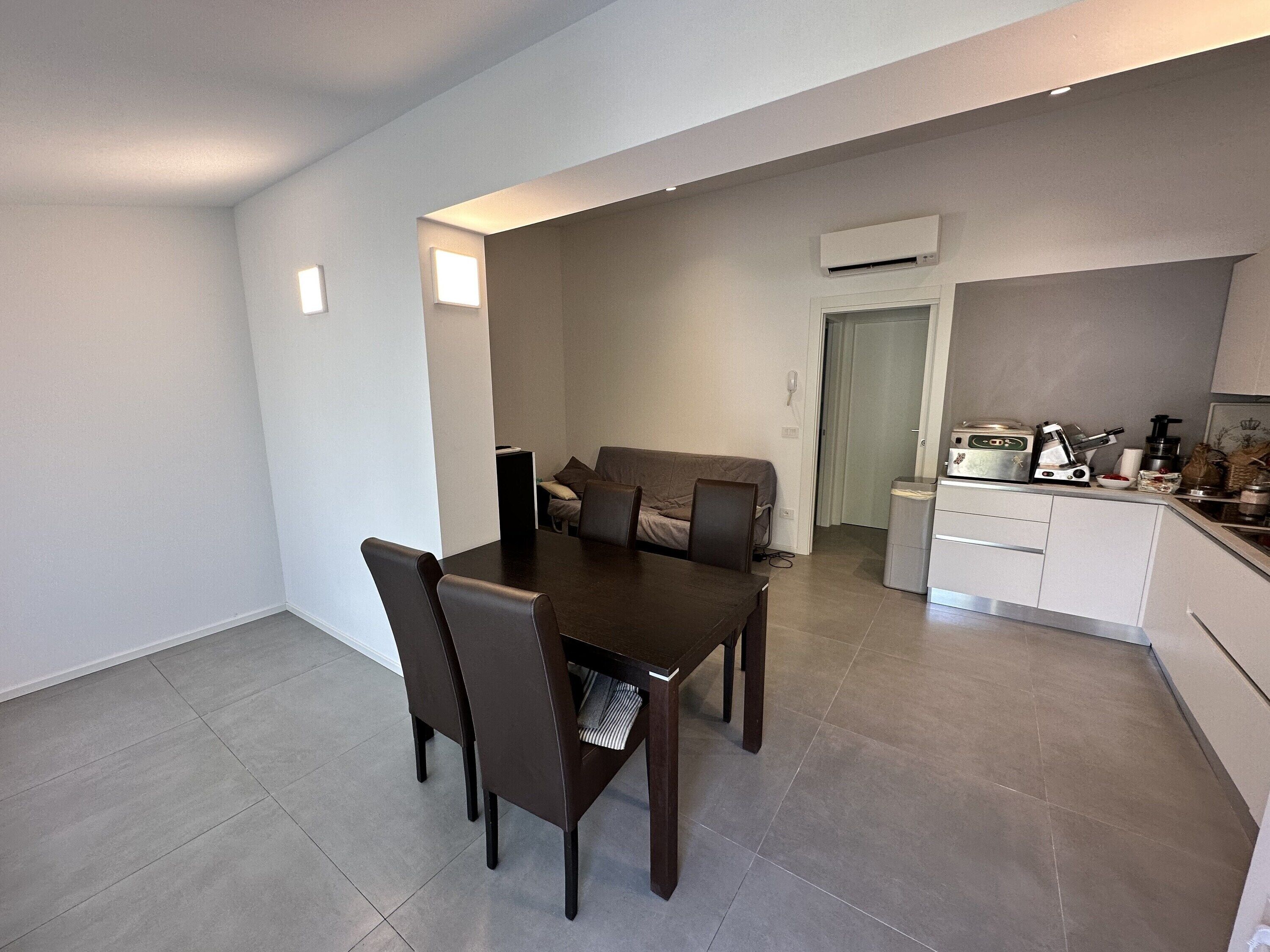 A modern kitchen with a coffee machine, a small refrigerator, and a dining area with a table and chairs.