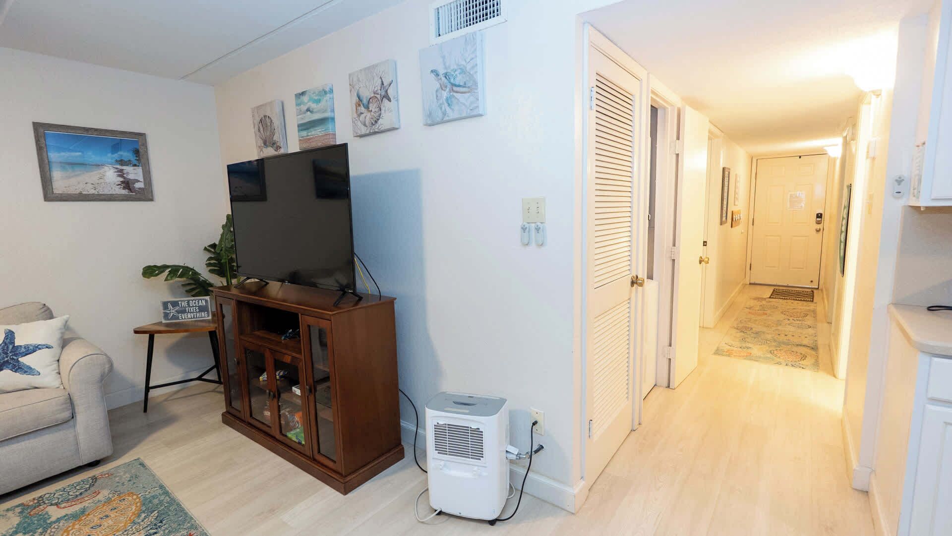 A living room with a TV, a plant, and artwork on the wall.