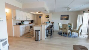 Una cocina moderna con armarios blancos, una isla central y un comedor con una mesa redonda y sillas.