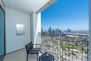 Ein Balkon mit Blick auf die Stadt, ein Sessel, ein kleiner Tisch und ein wandmontierter Spiegel.