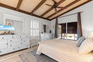 Una camera da letto con un letto, una cassettiera, una televisione e un balcone con vista.