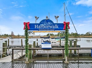 Een houten steiger met een bordje voor Harborwalk, versierd met kerstdecoratie.