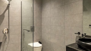 A modern bathroom with a glass shower enclosure, a white toilet, and a black sink with a mirror above it. - Elegant Studio Near Quba Mosque Prime Location (Madinah)
