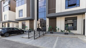 A modern building with a car parked in front, a staircase, and potted plants. - Elegant Studio Near Quba Mosque Prime Location (Madinah)