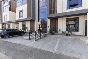 Un edificio moderno con un automóvil estacionado adelante, una escalera y plantas en macetas.