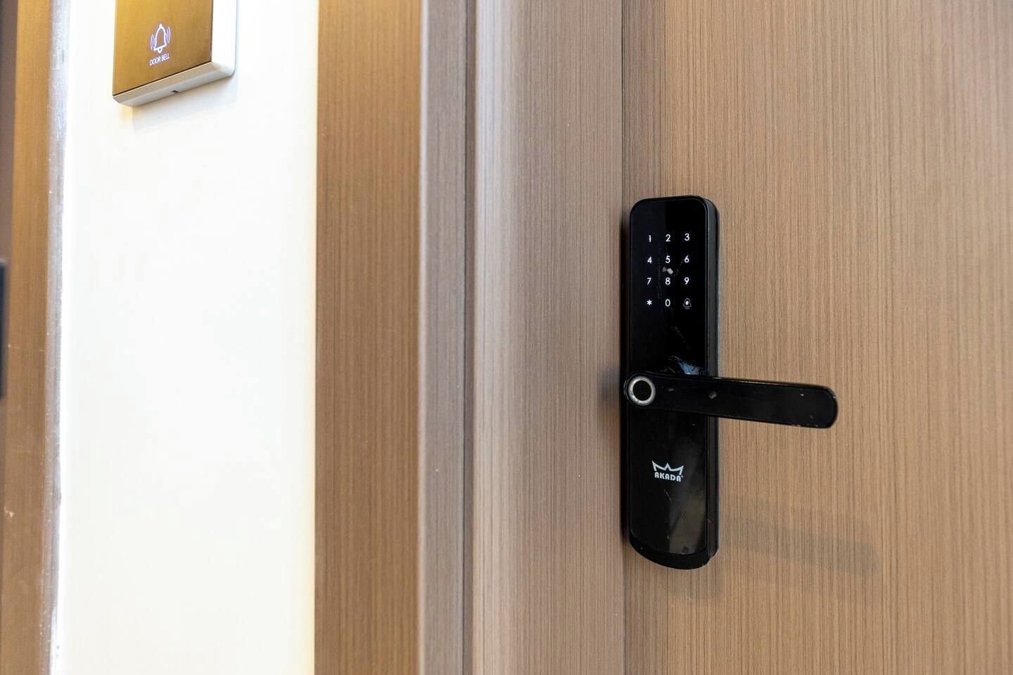 A modern door with a digital keypad lock and a doorbell.