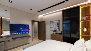 A modern hotel room with a large bed, a flat-screen TV mounted on the wall, a wooden cabinet, and a sliding door closet. - Elegant Studio Near Quba Mosque Prime Location (Madinah)