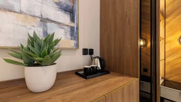 A wooden counter with a potted plant, a coffee maker, and a black mug.