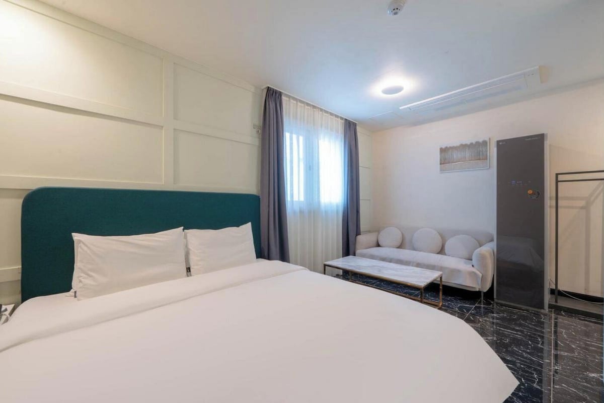 Una habitación de hotel con cama, sofá, escritorio y armario.