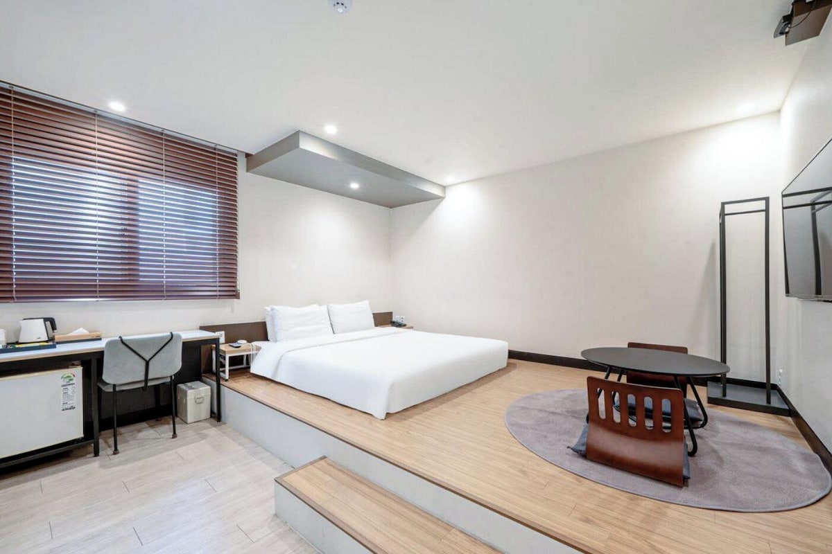 Una habitación de hotel moderna con cama, escritorio, silla y una pequeña mesa de comedor.