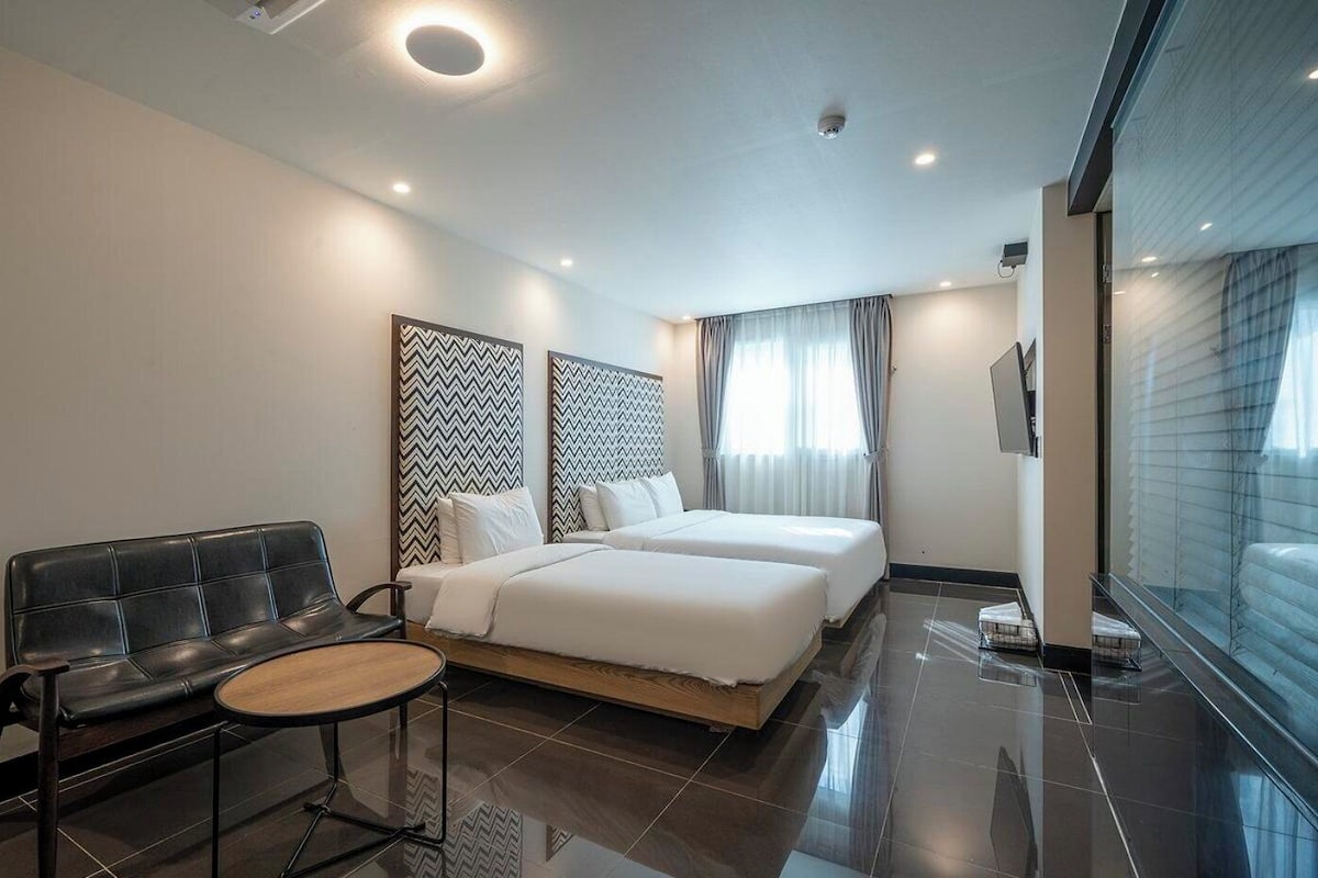 Una habitación de hotel con una cama, un sofá, una mesita y un televisor.