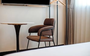 A chair and a table in a room with a television on the wall. - MU Plus Hotel Busan (Busan)
