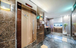 Un vestíbulo de hotel con una recepción, un reloj digital y una planta en maceta.