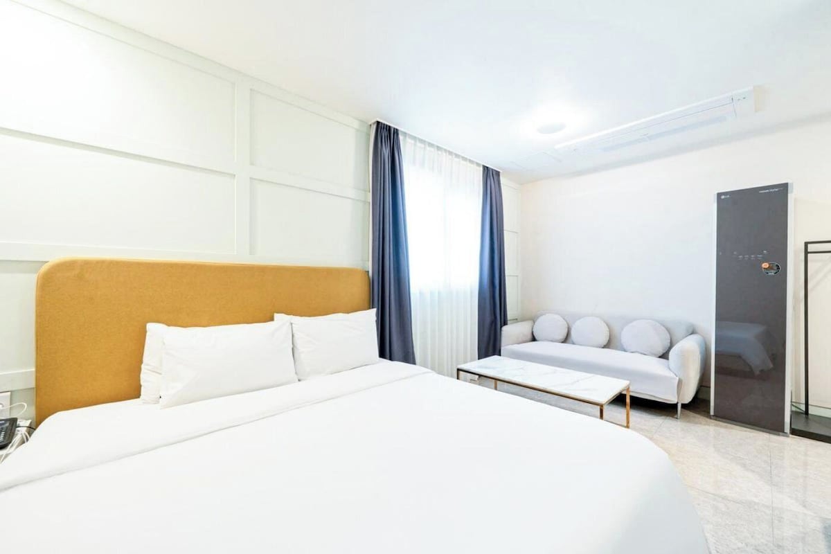 Una habitación de hotel con una cama grande, un sofá, una mesa de centro y un armario.