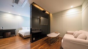 Ett modernt hotellrum med en säng, en soffa, ett litet bord och en tv.