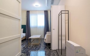 Habitación de hotel con cama, una mesita, cabina de ducha y suelo de mármol.