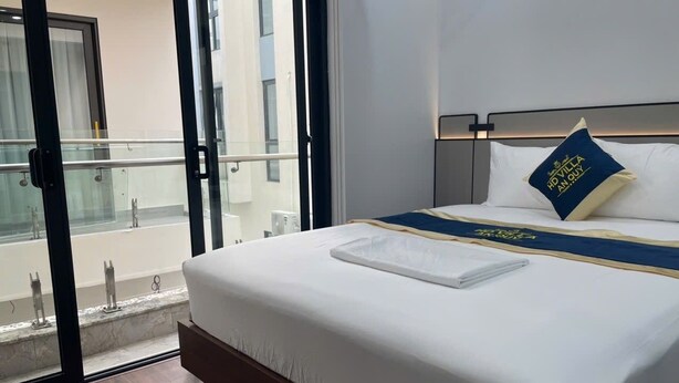 A hotel room with a bed, a view of the outside, and a balcony. - HD Villa Hotel An Quy - by BAY LUXURY (Hanoi)