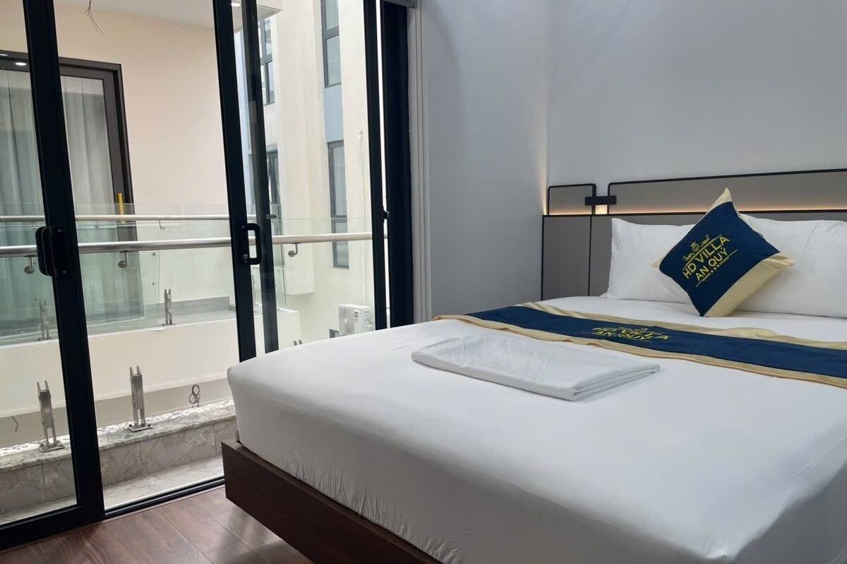A hotel room with a bed, a view of the outside, and a balcony.