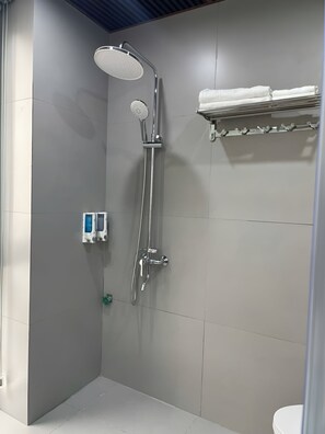 A shower with a handheld showerhead, a wall-mounted faucet, and a towel rack with towels. - HD Villa Hotel An Quy - by BAY LUXURY (Duong Noi)