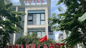 A hotel entrance with a modern design, a flag, and a promotional banner.