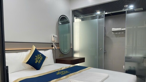 A hotel room with a bed, a bedside table with a lamp, a mirror, and a sliding door closet.