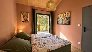 A bedroom with a bed, a door, and a view of an outdoor area. - Maison bois avec piscine au cœur du Périgord Noir (Nadaillac)