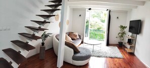 Ein modernes Wohnzimmer mit einer einzigartigen Wendeltreppe, einem bequemen Sofa, einem kleinen runden Tisch und einem Fernseher.