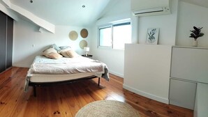 Ein Schlafzimmer mit Bett, Nachttisch, Lampe, Fenster und Heizkörper.