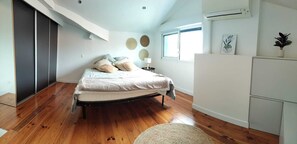 Ein Schlafzimmer mit Bett, Nachttisch, Lampe, Fenster und Heizkörper.