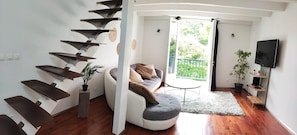 A modern living room with a spiral staircase, a sofa, a small round table, and a TV.