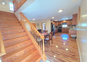 A spacious kitchen with wooden flooring, a dining area, and a staircase. - Elberon Escape-4BR Stay Near Bay,10 Min to Casinos (Atlantic City)