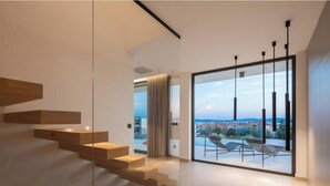 Un intérieur moderne avec un escalier, une porte vitrée donnant sur un balcon avec vue et un design minimaliste.