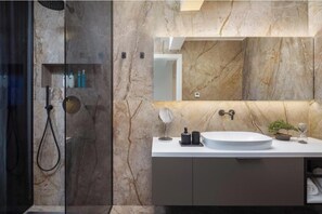 A modern bathroom with a marble wall, a sink with a mirror, and a shower area. - Villa 22 .. (ZADAR)
