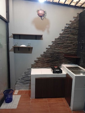Une cuisine avec un mur en pierre, un luminaire suspendu, une cuisiniÚre encastrée et un évier.