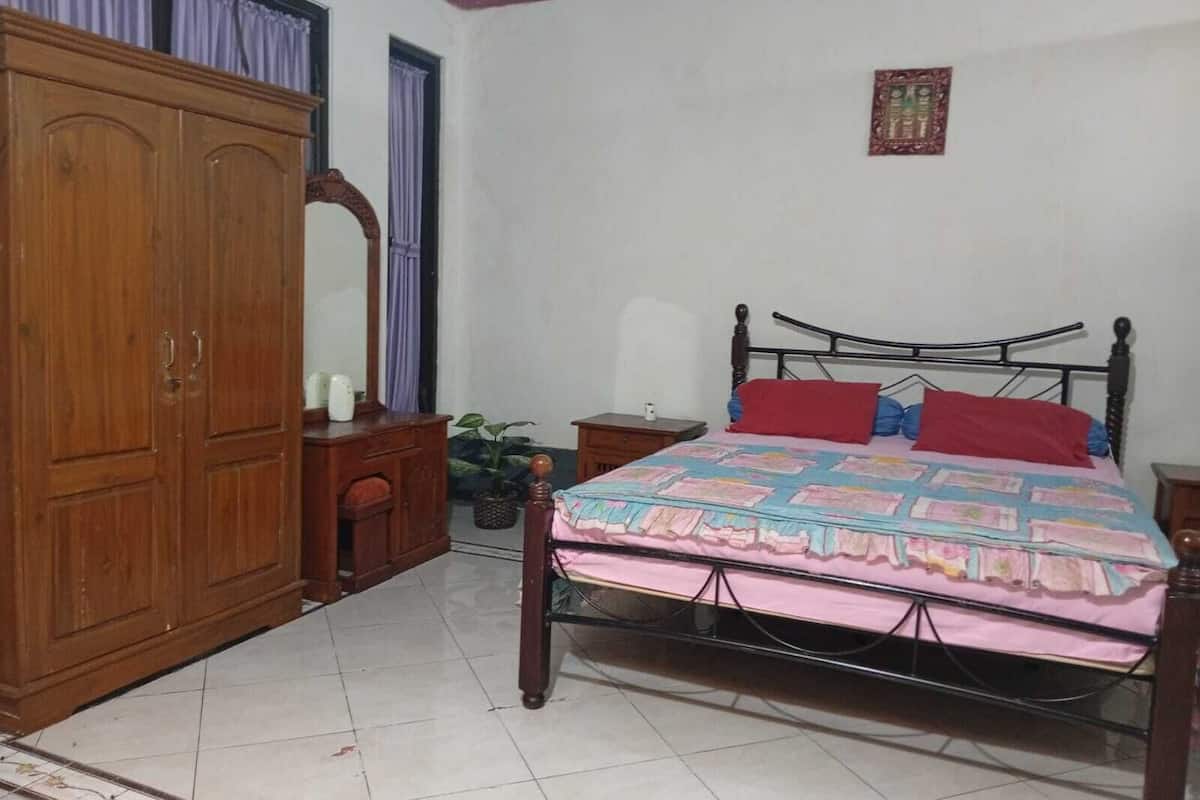 Un dormitorio con cama, armario de madera y una mesita con una planta.