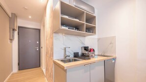 A compact kitchen with a built-in dishwasher, a coffee maker, and a small refrigerator. - Stylish Studio KingBed&Workspace-WkndNse (Athina)