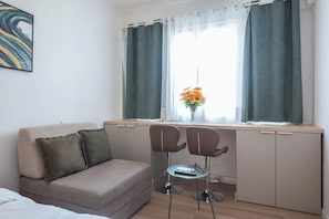 A room with a sofa, two chairs, a desk, and a window with curtains. - Stylish Studio KingBed&Workspace-WkndNse (Athina)