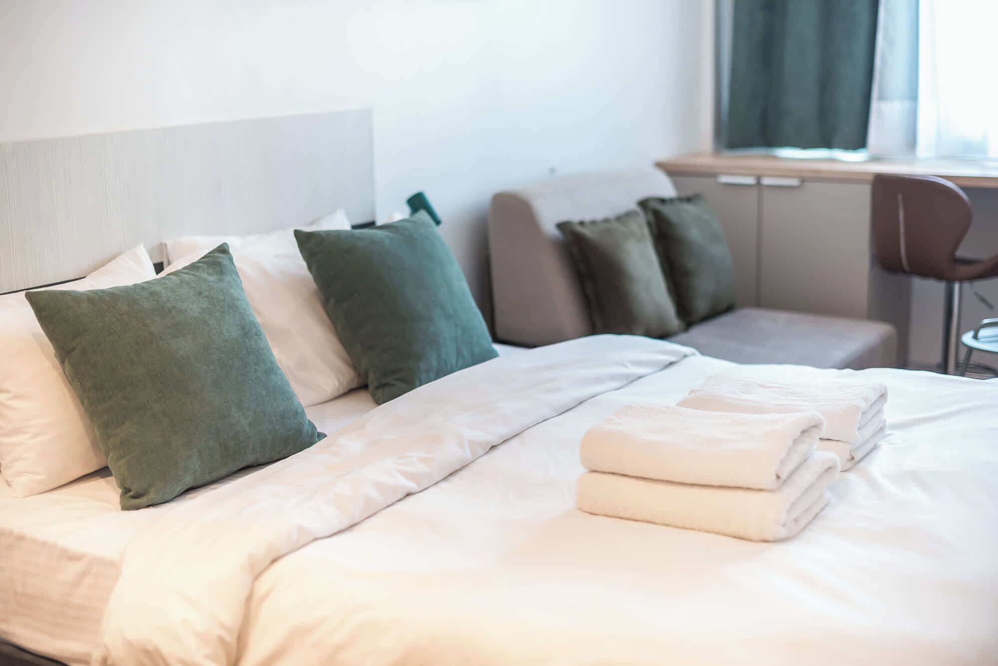 A hotel room with a bed, two bedside tables, a desk, and a chair.