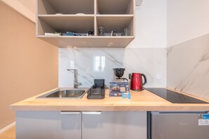 A compact kitchen with a sink, a coffee maker, a kettle, and a microwave. - Stylish Studio KingBed&Workspace-WkndNse (Athina)