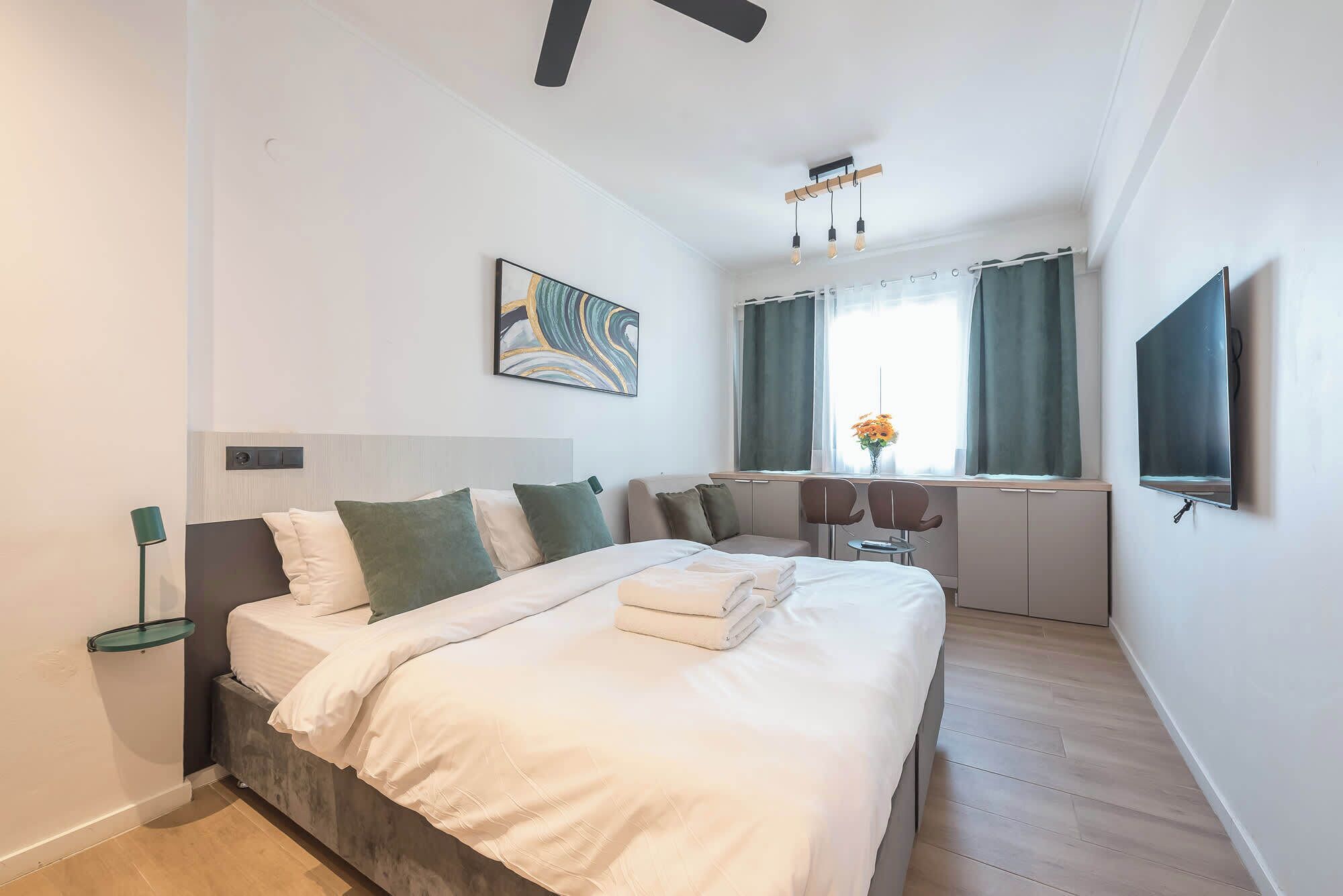 A modern bedroom with a bed, bedside table, and a desk area with a chair.