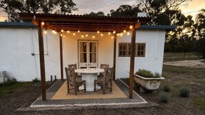 Un patio con un tavolo rotondo e sedie, un braciere e luci decorative.