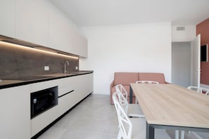 Eine moderne Küche mit integrierten Geräten, ein Essbereich mit Holztisch und Stühlen sowie eine neutrale Farbgestaltung.