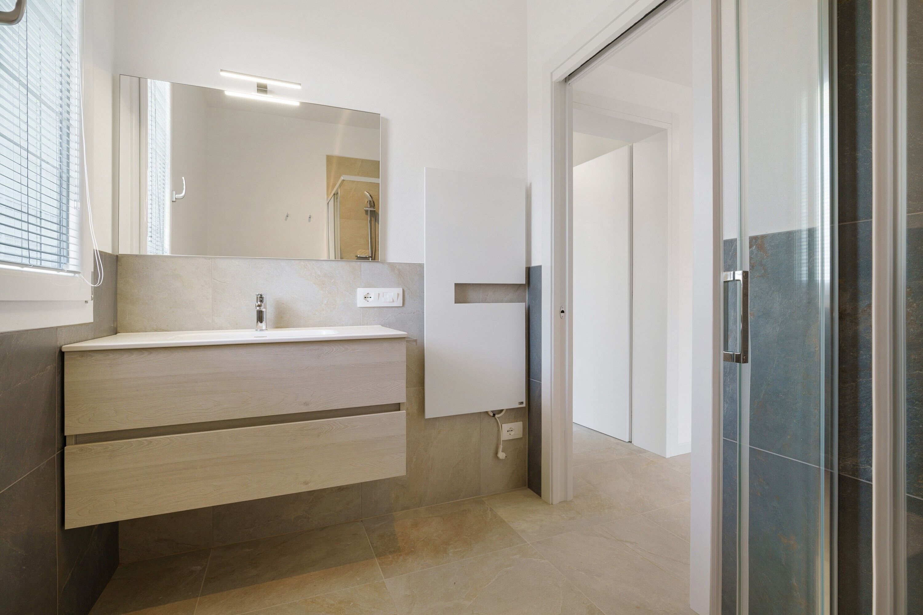 Une salle de bain moderne avec un meuble-lavabo, un miroir et un espace douche.