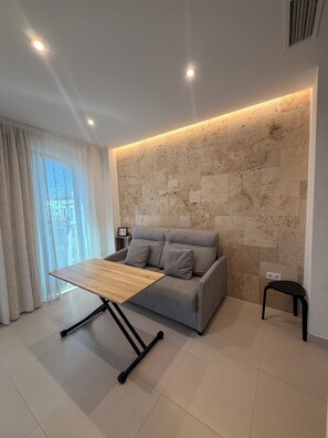 Una sala de estar moderna con un sofá, una mesa de centro de madera y una pared de piedra.