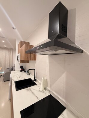 Una cocina moderna con estufa integrada, extractor de humos y encimera de mármol.