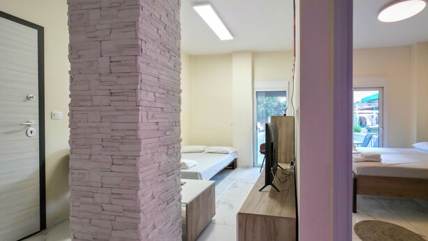 Ein Hotelzimmer mit einer Wand aus Stein, einem Bett, einem Holztisch und einem Fernseher.