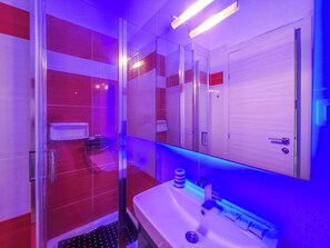 Ein Badezimmer mit Duschkabine, Waschbecken und Spiegel.