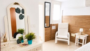 Une chambre moderne avec un mur d’accent en bois, une commode blanche agrémentée de miroirs décoratifs, une chaise blanche et une table de chevet avec une lampe.